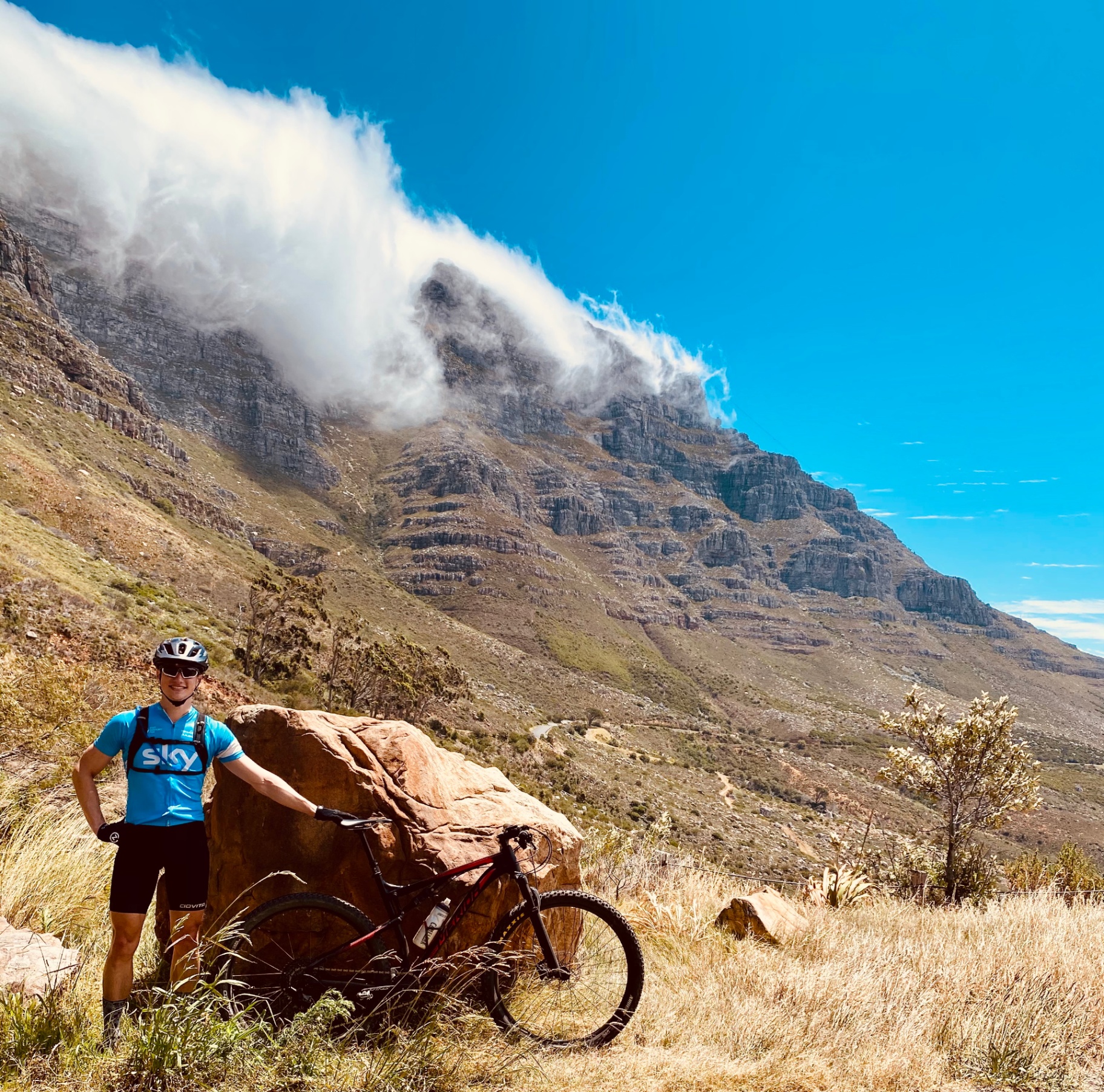 Rider posing beside a granite boulder under cloud-draped cliffs