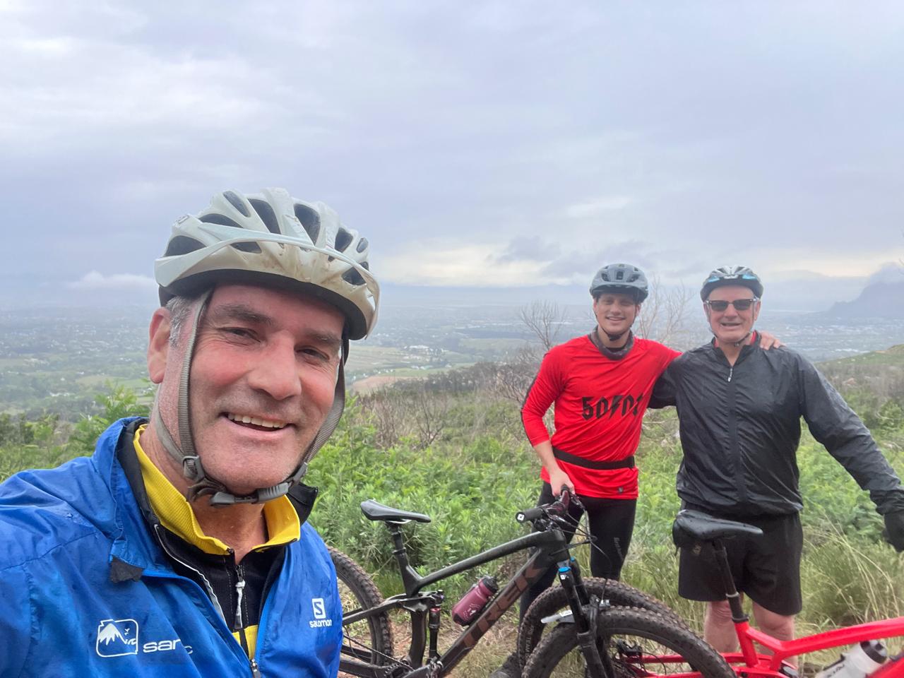 Three riders posing together on a misty hillside trail
